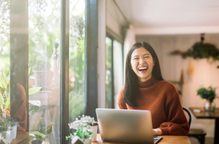 A smiling female in front of her laptop